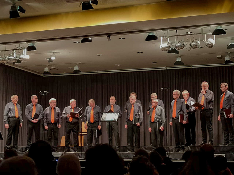 Der VokalExpress des MGV Windesheim am 15. April 2023 auf der Bühne der Domberghalle in Waldlaubersheim. In der Mitte das Moderatoren-Duo des Abends, Wilhelm Reimann und Günter Stauer.